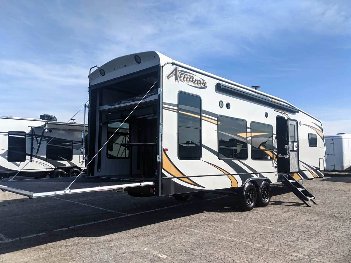 A toy hauler travel trailer with garage door open.