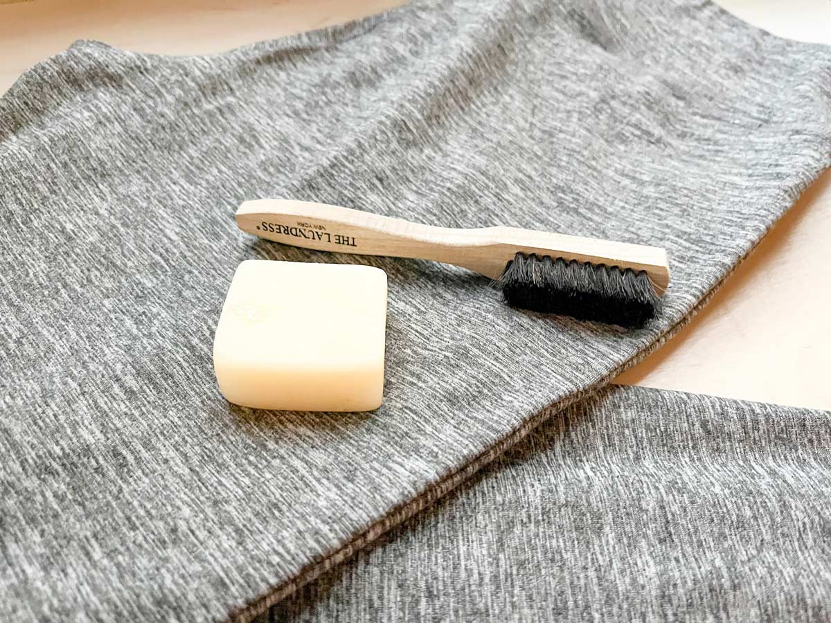 Fabric cleaning brush and stain remover bar on top of a pair of leggings.