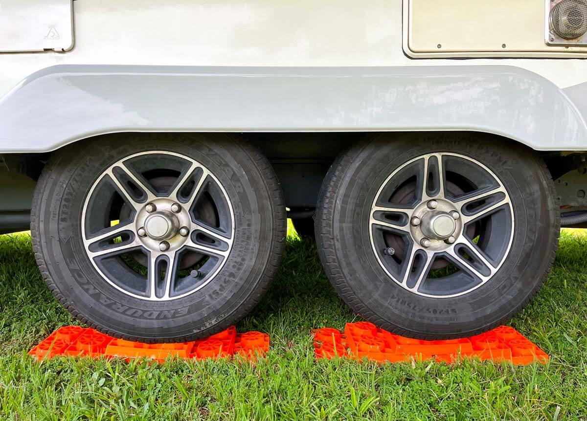 Leveling blocks under RV tires on a grassy surface.