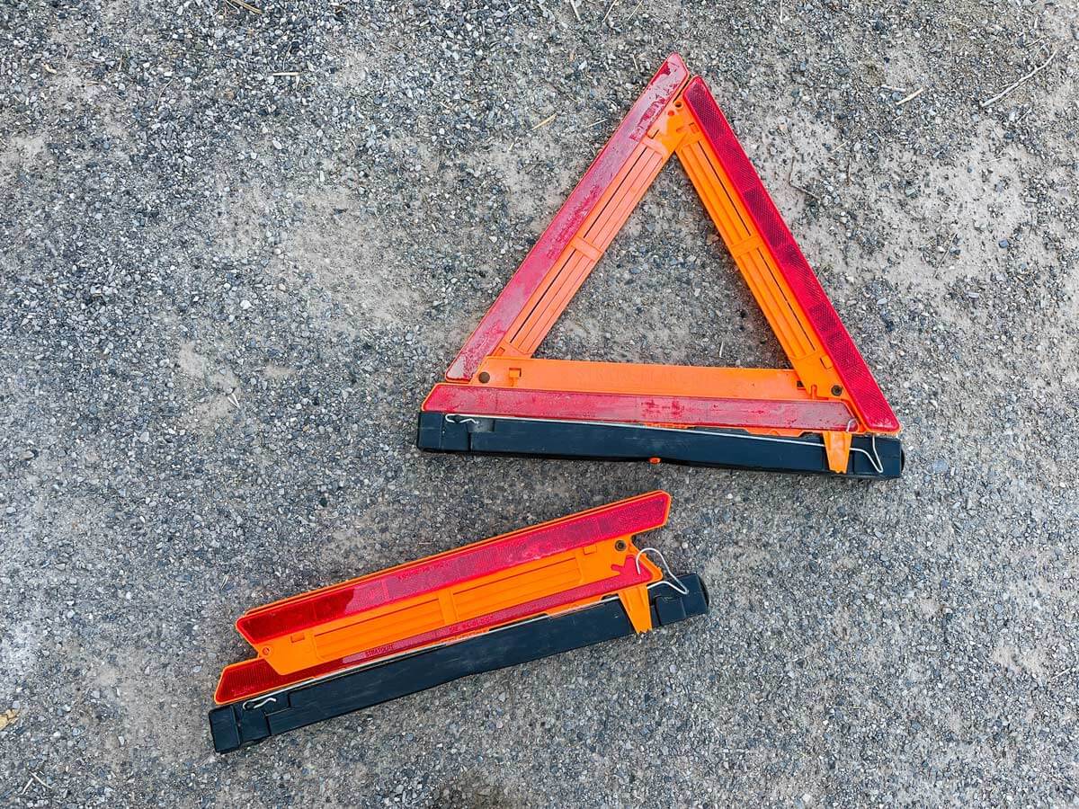 Road safety triangles on the ground. One is folded for storage and another is open for use.