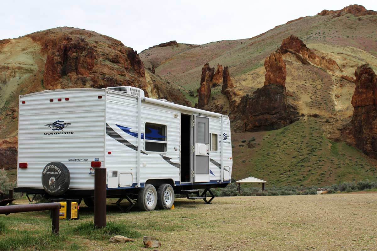 Travel trailer parked in the desert at a rural campsite.