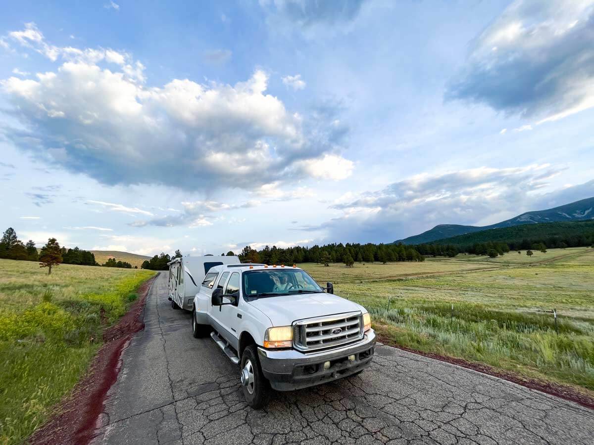 F350 towing a travel trailer on a back road in the mountains.