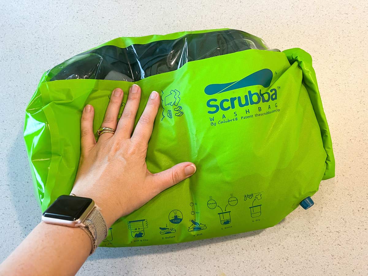 Scrubba wash bag full of clothes being rubbed back and forth to launder them.