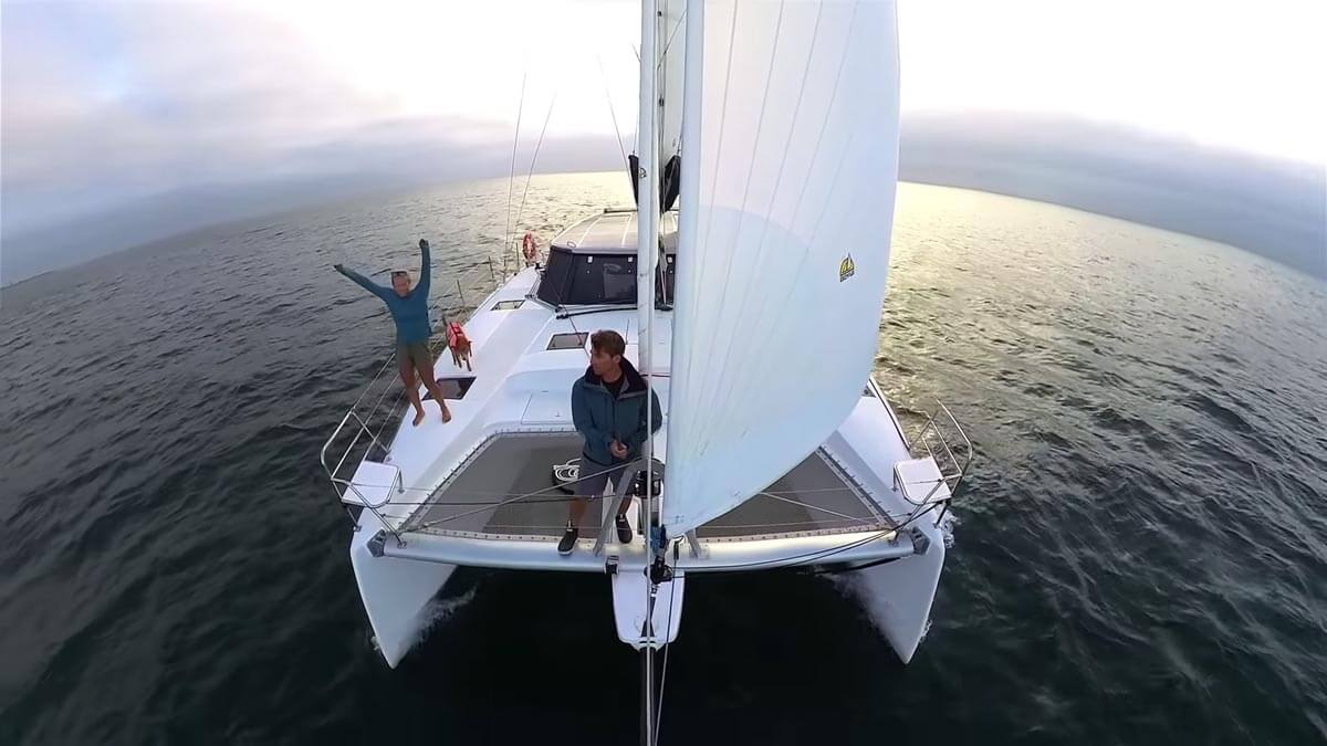 Screenshot of Tula's Endless Summer's video of the front of the catamaran while under sail and crew out on the bow.
